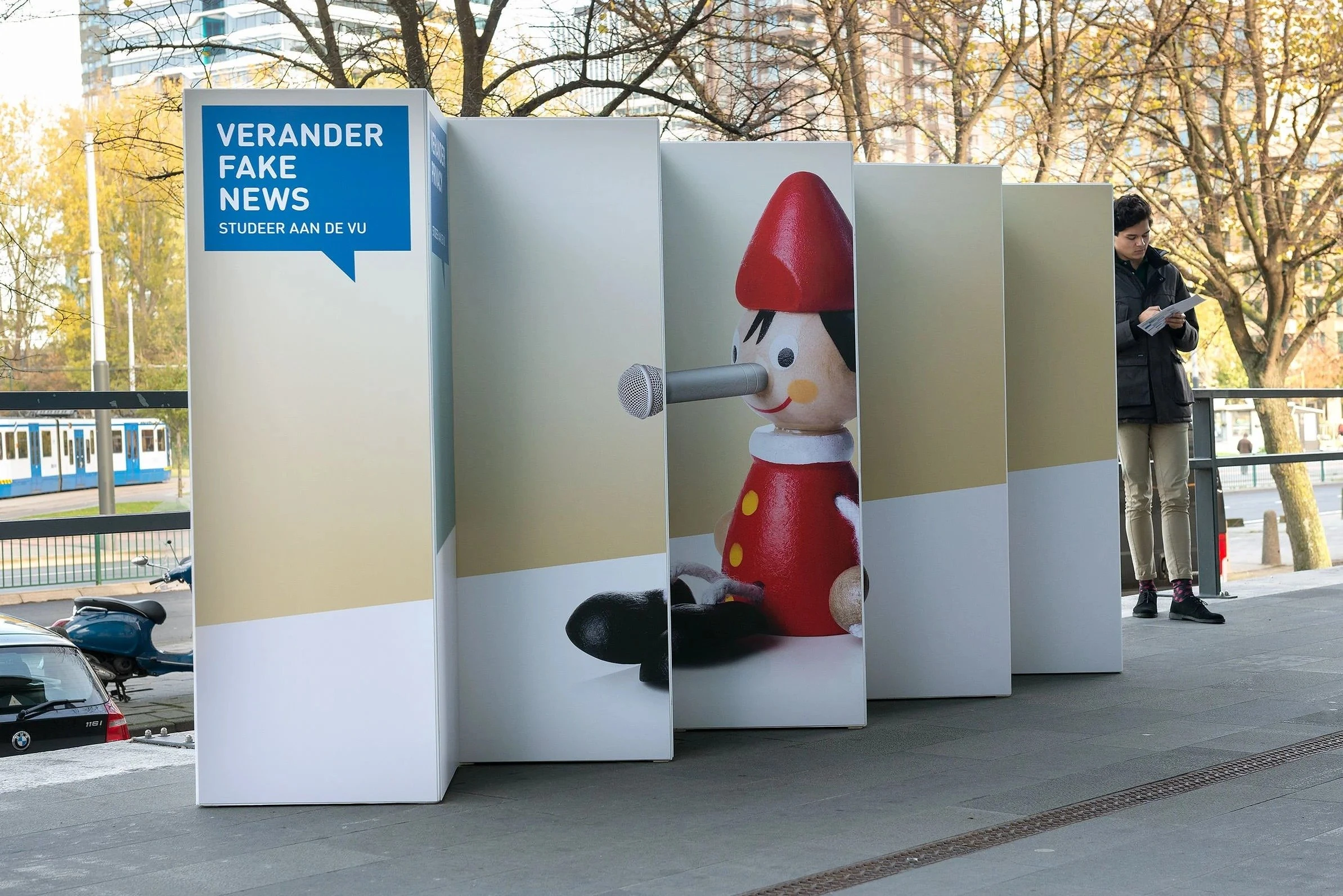 Buitenreclame VU open dag: "Verander fake news", Pinokkio met lange neus tussen witte panelen